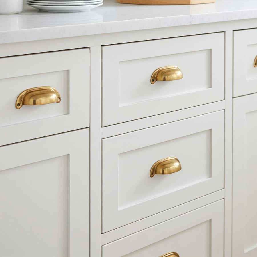 Unlacquered brass half moon cup pulls fitted on white shaker drawer fronts